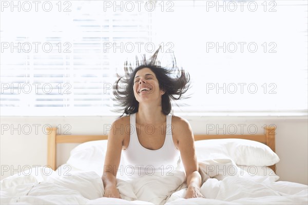 Smiling Hispanic woman sitting in bed
