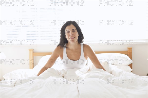 Smiling Hispanic woman sitting in bed