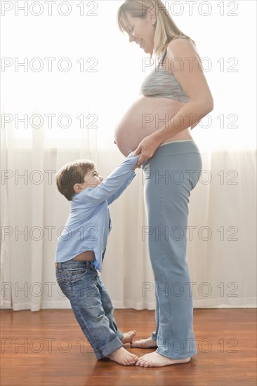 Pregnant Caucasian mother holding hands with son