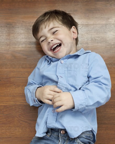 Laughing Caucasian boy laying on floor