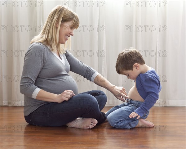 Pregnant Caucasian mother sitting on floor with son