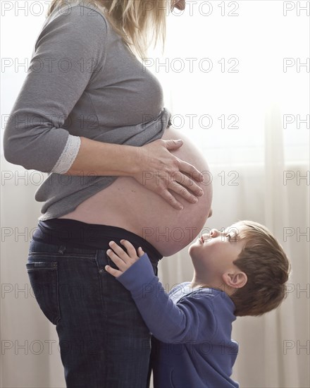 Caucasian boy looking at pregnant woman's stomach