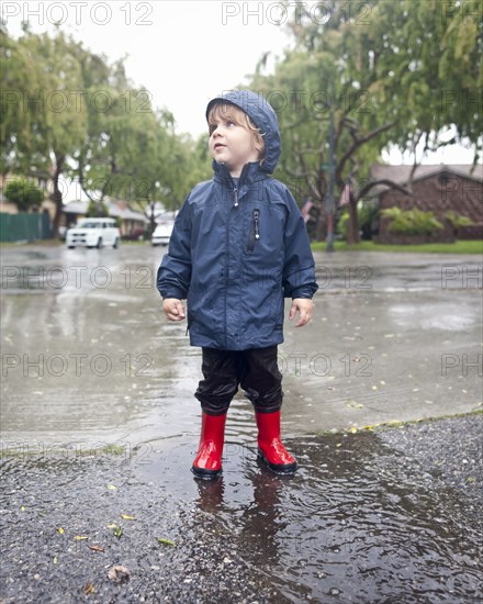 Caucasian boy standing in rain