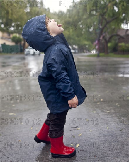 Caucasian boy catching raindrops on tongue