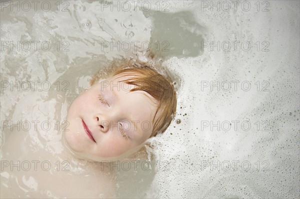 Caucasian boy with eyes closed in bubble bath
