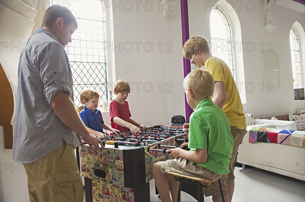 Caucasian father and sons playing foosball