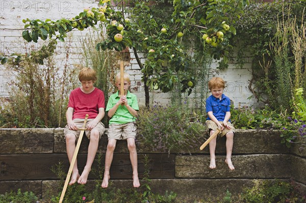 Caucasian brothers holding toy swords in backyard