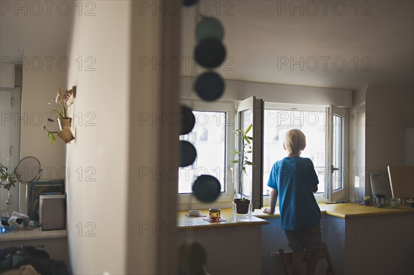 Caucasian boy looking out kitchen window