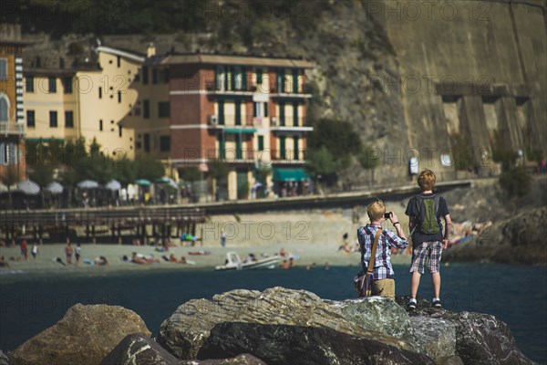 Caucasian brothers photographing beach from rock formations