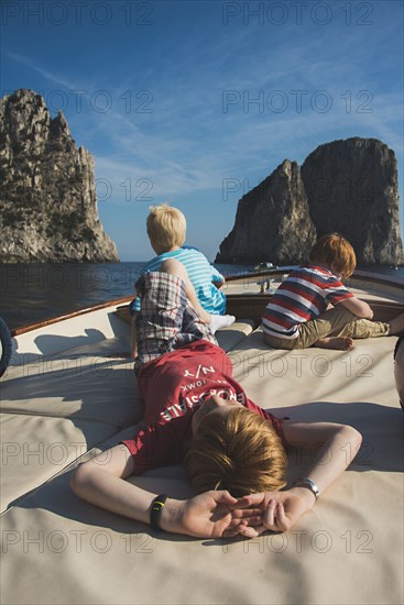 Caucasian brothers on boat admiring rock formations and ocean