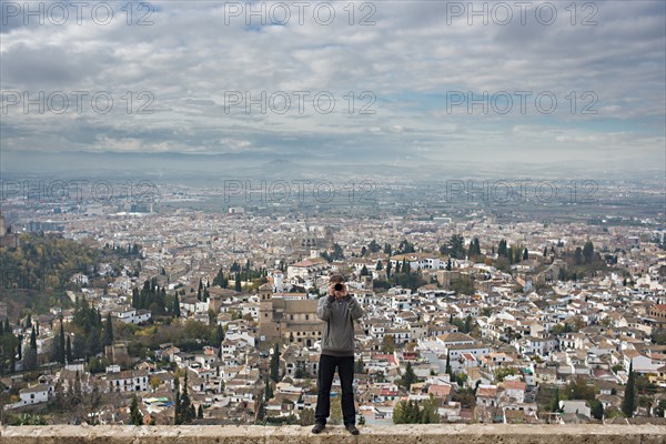 Caucasian tourist on wall over scenic view of cityscape