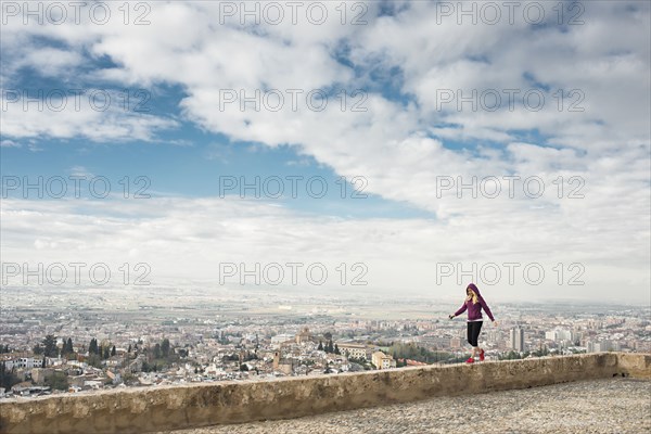 Caucasian woman on wall overlooking scenic view of cityscape