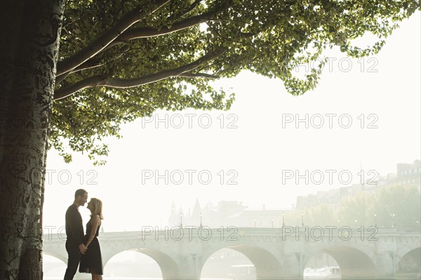 Caucasian couple kissing near bridge