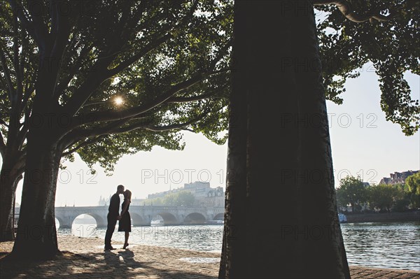 Caucasian couple kissing near bridge