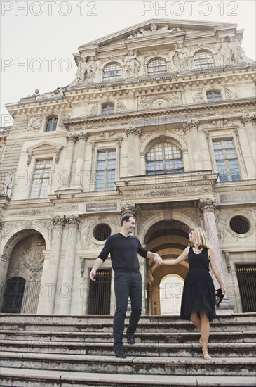 Caucasian couple walking on ornate building steps