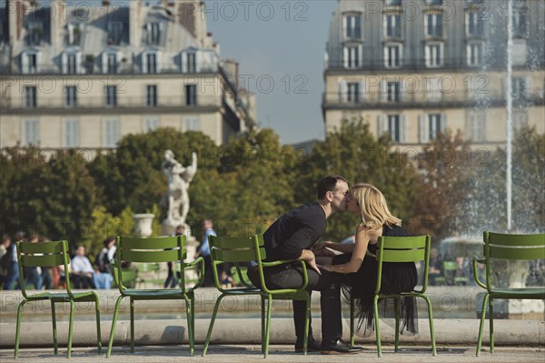 Caucasian couple kissing near fountain in urban park
