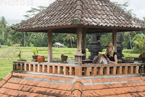 Caucasian woman reading book on rooftop balcony