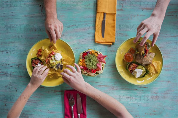 High angle view of hands reaching for food on plates