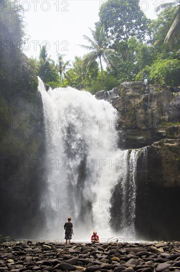 Caucasian tourists admiring waterfall in jungle