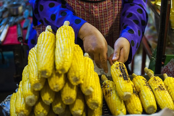 Close up of seller grilling corn at market