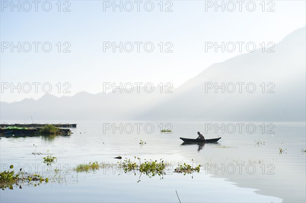 Man rowing canoe on still remote lake