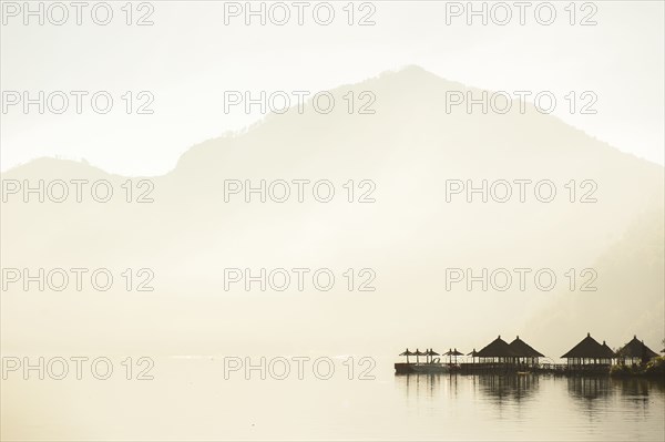 Huts reflecting in still remote lake under mountains