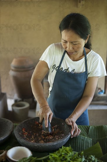 Asian chef grinding spices in outdoor kitchen