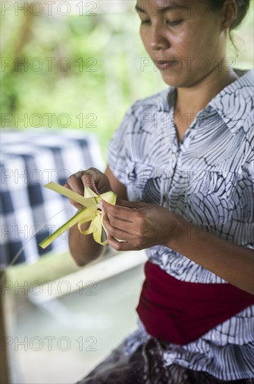 Asian woman knotting leaves outdoors