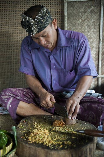 Asian man grinding spices on cutting board