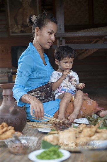 Asian mother and son eating on woven mat