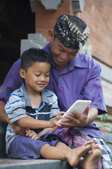 Asian father and son using cell phone outdoors