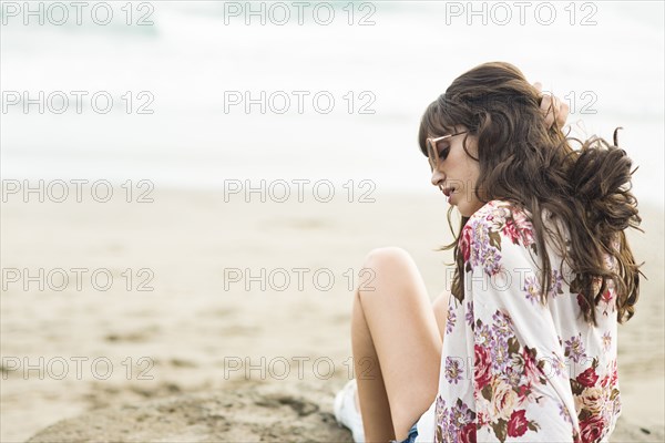 Caucasian woman sitting in sand on beach