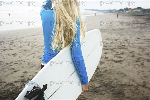 Caucasian surfer carrying surfboard on beach