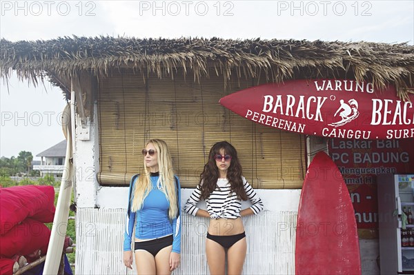 Caucasian women standing at surf hut on beach