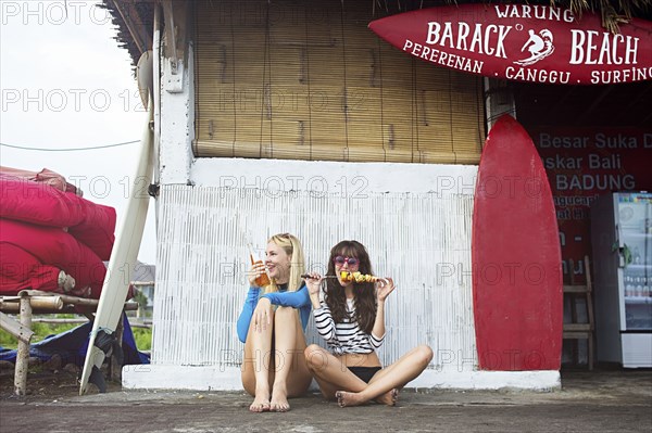 Caucasian women eating at surf hut on beach