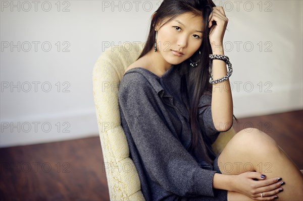 Asian woman sitting in armchair