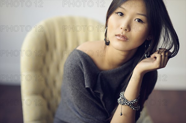 Asian woman sitting in armchair