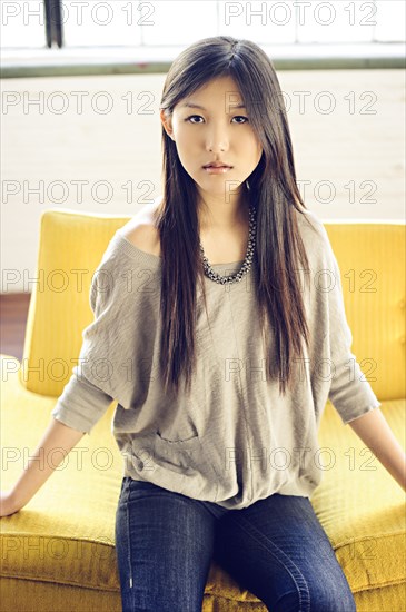 Asian woman sitting on yellow sofa