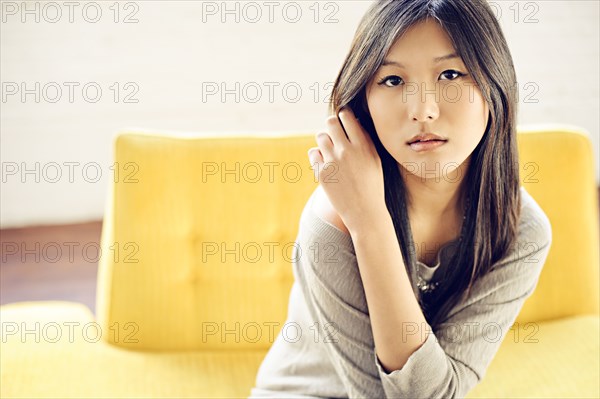 Asian woman sitting on yellow sofa