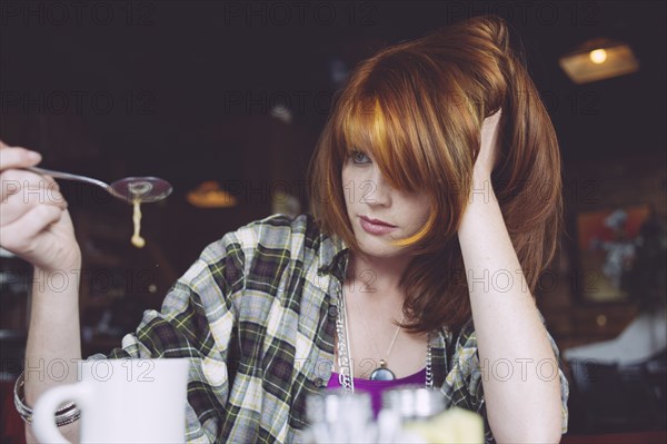 Caucasian woman playing with coffee in cafe