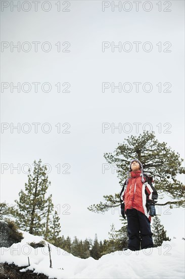 Boy standing in snow and looking up