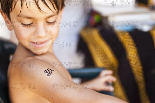 Mixed race boy looking at temporary tattoo