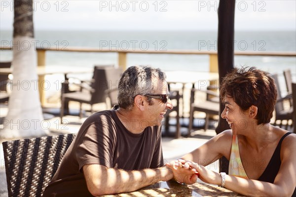 Smiling couple sitting on resort patio holding hands