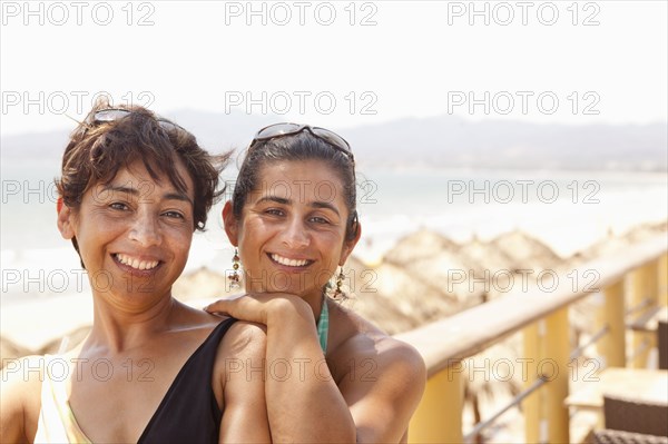 Smiling Hispanic woman standing together on balcony