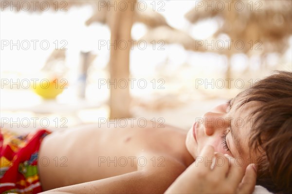 Sleeping mixed race boy laying on beach