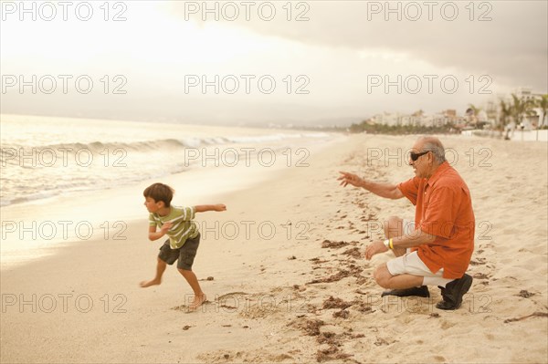 Grandfather and grandson playing on beach together