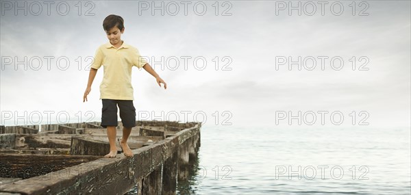Mixed race boy walking on dilapidated pier