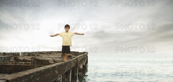 Mixed race boy walking on dilapidated pier