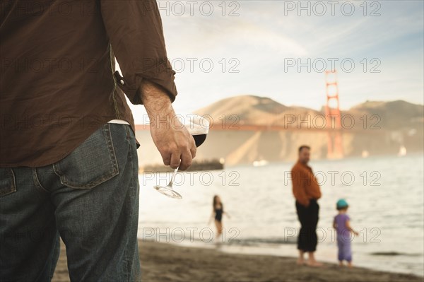 Caucasian man drinking wine on beach