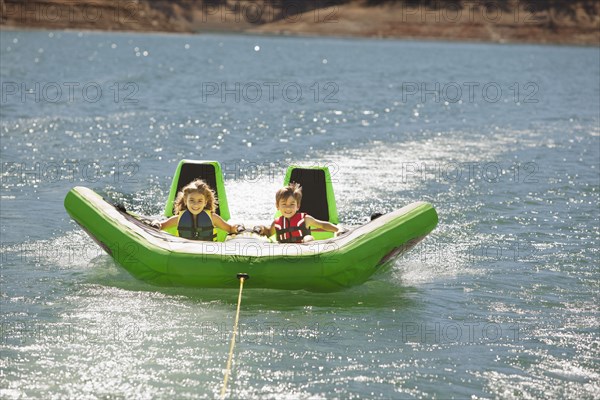 Children riding inflatable raft on lake